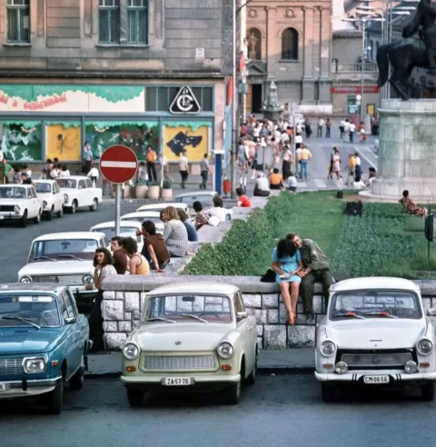 Főként fiatalok beszélgetnek a parkoló autók mellett a Széchenyi téren, Pécsett….